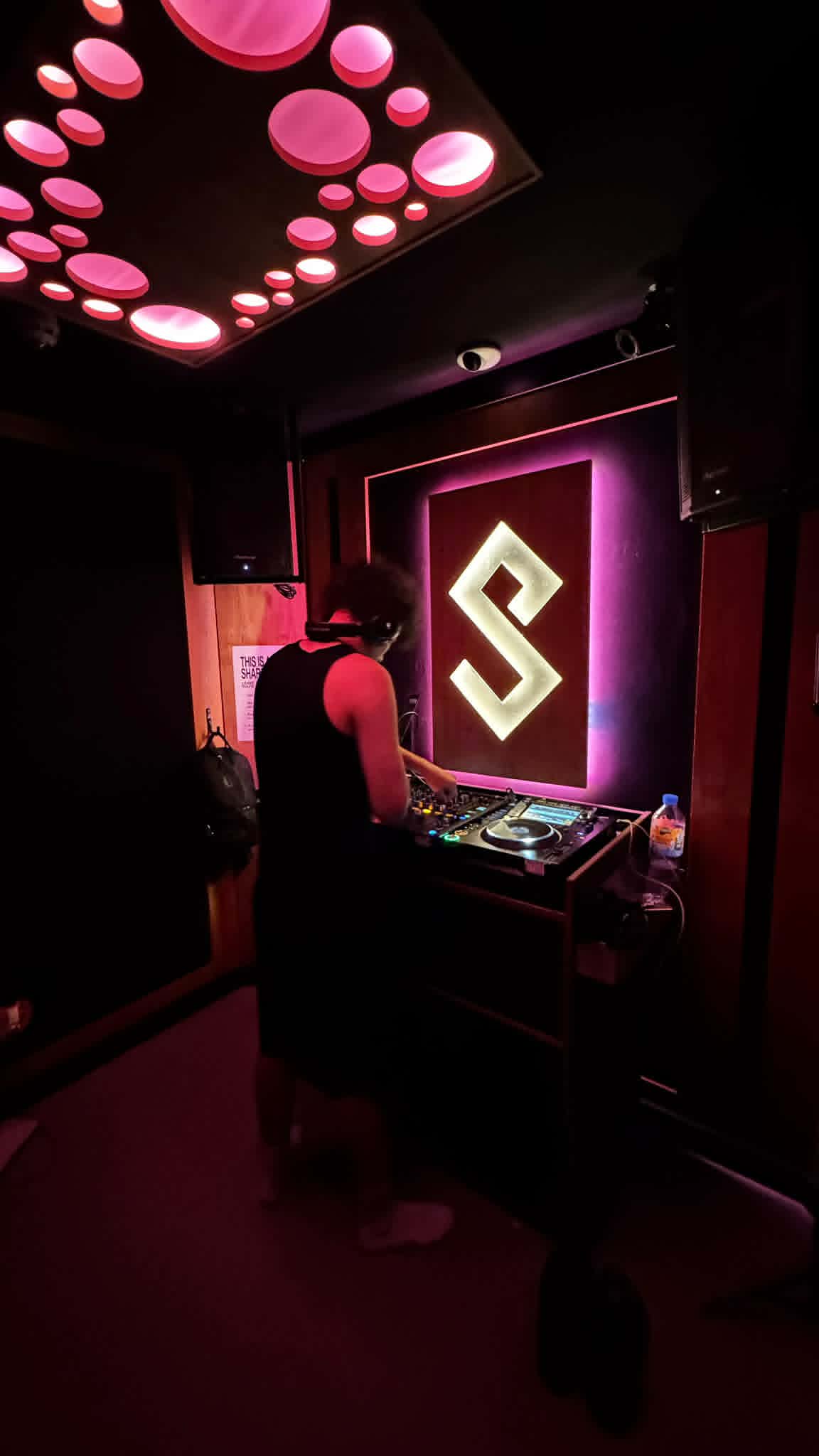 DJ KOZZ performing under pink club lighting